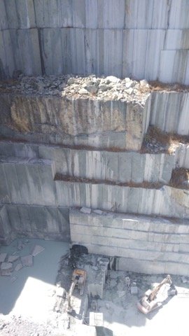 Benched quarry face with exposed mineral seams